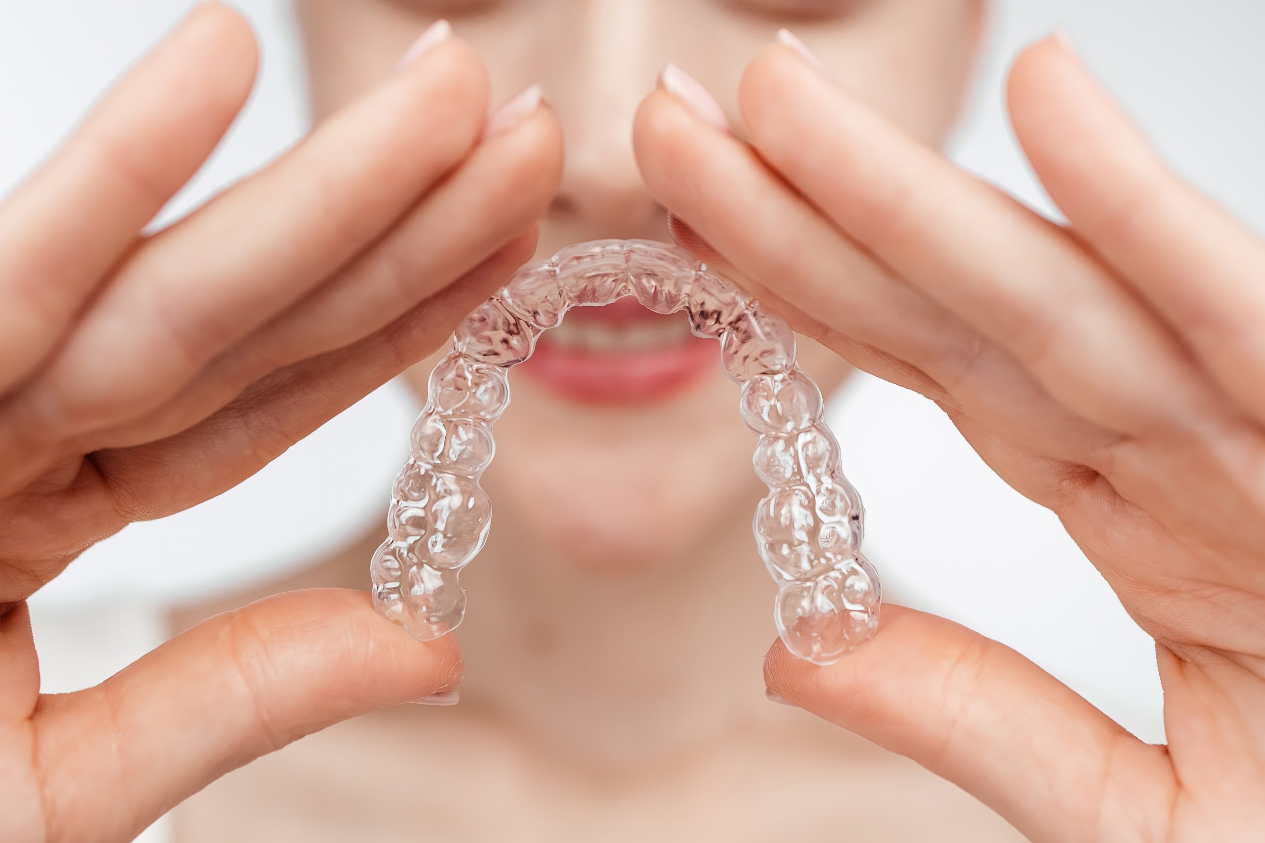 close up woman demonstrate clear teeth aligner for orthodontal straightening treatment. perfect for promoting dental services. isolated white background. removable invisible braces aligner